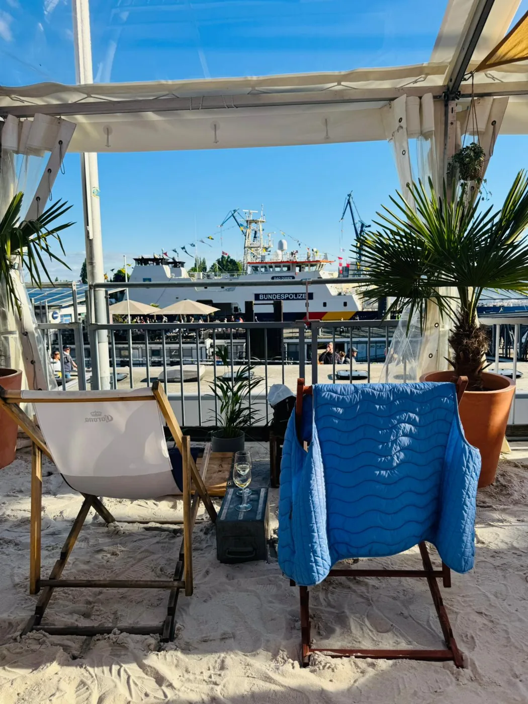 Liegestühle im Sand des StrandPauli Beachclubs mit Blick auf die Elbe